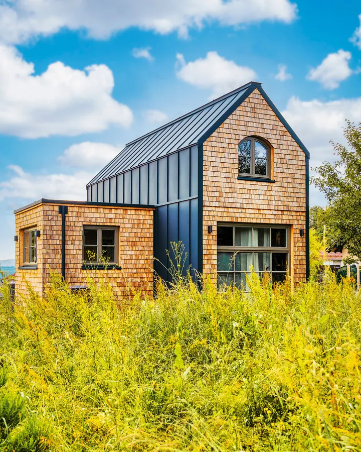 Tiny House mit Holzschindel-Fassade in einer blühenden Wiese