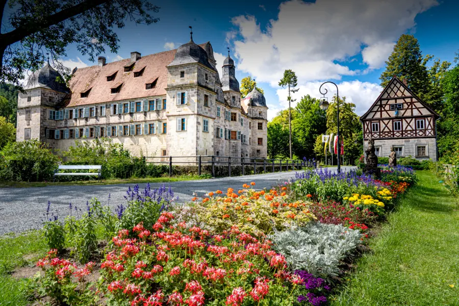 Wasserschloss Mitwitz mit blühendem Garten im Sommer